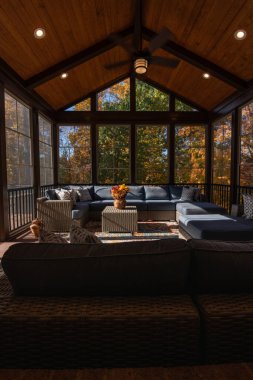 Şükran Günü 'nde modern mobilyalarla çevrili samimi sundurma. Vazoda çiçek buketi, sonbahar yaprakları ve arka planda orman..