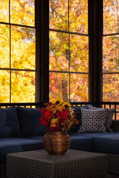 stock image Cozy screened porch enclosure view in autumn. Flower bouquet in a vase, autumn leaves and woods in the background.