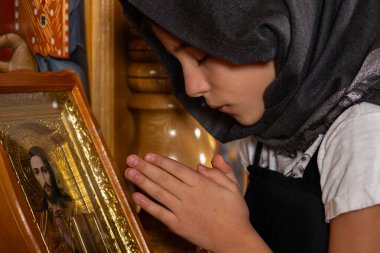 Kilise kürsüsünde İsa 'nın simgesi önünde dua eden genç bir kız..