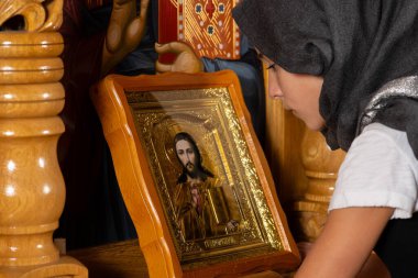 Kilise kürsüsünde İsa 'nın simgesi önünde dua eden genç bir kız..
