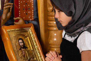Kilise kürsüsünde İsa 'nın simgesi önünde dua eden genç bir kız..
