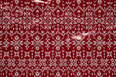 Kırmızı arka planda beyaz kar taneleri buruşmuş ambalaj kağıdı. Noel Tatili Konsepti.