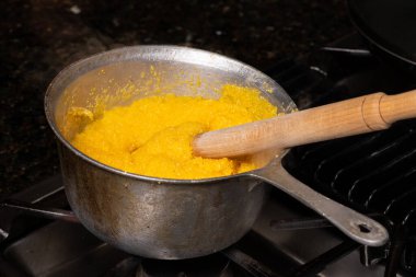 Bir ocağın tepesinde polenta pişirmek, geleneksel bir mısır unu yemeği..