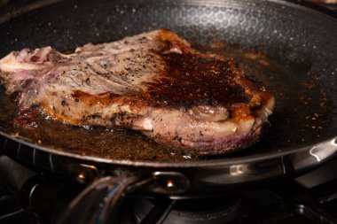 Biftek kızartma tavasında yüksek sıcaklıkta pişiyor..