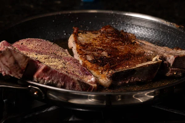 Beef steak cooking at high temperature in a frying pan.
