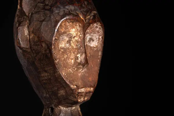 An African male figure portrait carved in wood isolated on black. Traditional African art with balanced shapes and volumes and beautiful black patina and kaolin pigments.
