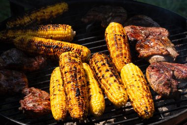 Mısır ve etle ızgara, güzel yanmış altın mısırlar sergileniyor. Bu her yaz yapılan barbekü partisinin en önemli olayıdır..