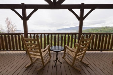 Ahşap sallanan sandalyeleri ve küçük bir masası olan büyüleyici kabin güvertesi sisli Smoky Dağları 'nın huzurlu bir manzarasını sunuyor. Rahatlamak ve doğa severler için idealdir..