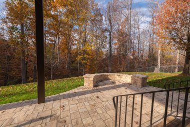 Arka bahçesinde taş kaldırımlar ve siyah metal parmaklıklarla çerçevelenmiş eğri bir taş duvar var. Düşen yapraklar ve sonbahar yaprakları sıcak, mevsimsel bir atmosfer yaratır..