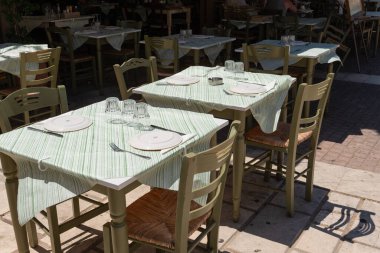 Yunanistan 'ın Zakynthos kentindeki misafirler için geleneksel Yunan taverna masası tabaklar ve cam örtülerle gölgelenmiş ve hazır.