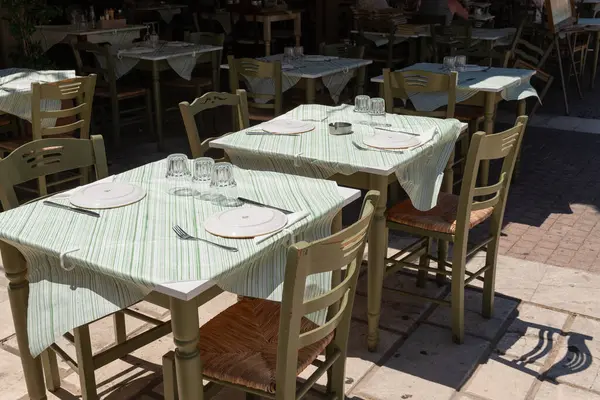 Yunanistan 'ın Zakynthos kentindeki misafirler için geleneksel Yunan taverna masası tabaklar ve cam örtülerle gölgelenmiş ve hazır.