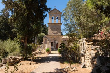 Dermatousa Kilisesi taştan manastırı. Huzurlu Zakynthos kırsalındaki ağaçların arasına yerleştirilmiş ikiz çan kulesi..