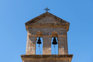 Yunanistan 'ın Zakynthos kentindeki Dermatousa Kilisesi' nin tarihi çan kulesinde açık mavi bir gökyüzünün altında ikiz çanlar asılı..