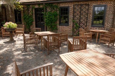 Middleton Place Plantation, Charleston, SC 'deki Middleton Place Restoranı' nın dışındaki güneşli avluda ahşap yemek masaları ve sandalyelerin yakın çekimi..