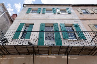 Charleston, Güney Carolina, ABD. 2 Temmuz 2025. İşlenmiş demir balkonu ve yeşil kepenkleri olan tarihi pastel mimari, güneyli cazibesini ve geleneğini yansıtıyor..