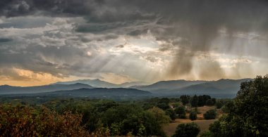 Taşra, dağlar, gökyüzü, bulutları delip geçen güneş ışınları.