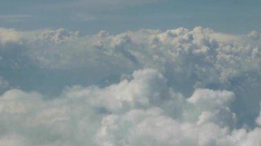 Bulutlu ve mavi gökyüzünden geçen uçak sağdan sola kayıyor.