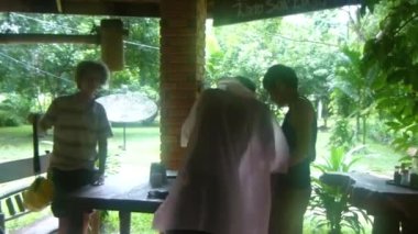 Barınak altındaki kadınlar Flora 'ya yağmur yağarken. Soldan Sağa Görüntü