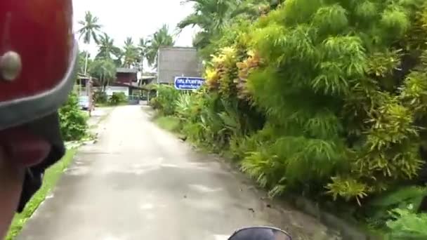 在农村地区骑摩托车靠近植物 建筑物和汽车 向前滑行 — 图库视频影像
