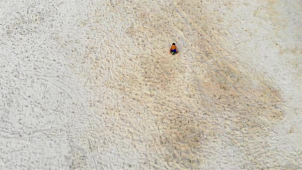 砂の中で遊んで青いショートパンツの子供のトップビュー クレーンダウン — ストック動画