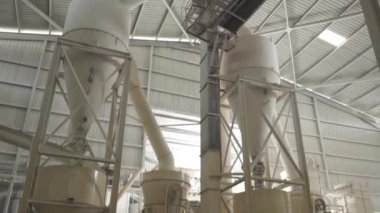 Beyaz çuvalı dolduran güvenlik teçhizatlı işçiler aşağı doğru eğiliyor.