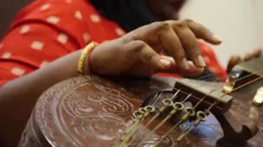 Yerde oturan kadın enstrüman çalıyor. Görüntüleri yakın çekimde kaydır.