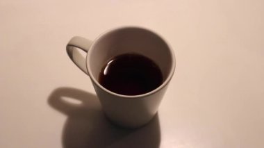 Bir çay kaşığı şekeri sade kahveyle bardağa atmak. Yakın çekim.