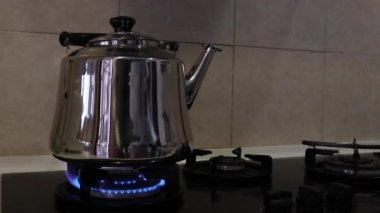Gaz ocağındaki gümüş çaydanlık, orta pişmiş.
