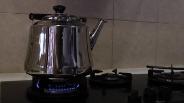 Gaz sobasının üstünde yüksek ısıda çay ısıtıcısı kaynıyor.