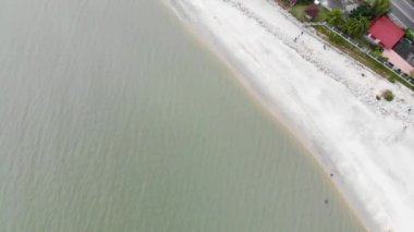 Beyaz kumlu egzotik sahilde soldan sağa hareket eden kulübelerin hava manzarası.