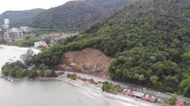 Tropikal yeşil dağların ve deniz kıyısına yakın binaların insansız hava aracı görüntüsü