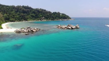 Yeşillik yakınlarındaki kayalık sahil manzarası sağdan sola hareket ediyor.