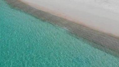 Beyaz kumsaldaki durgun deniz dalgalarının drone görüntüsü