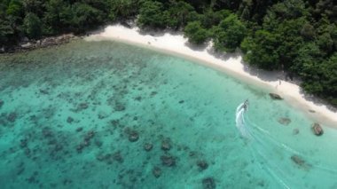 Tropikal drone görüntüsü beyaz kumlu kayalık kıyıya ulaşıyor.