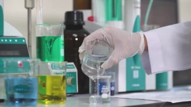 Eldivenli bir adam kalite testi için boya ve solüsyon katıyor.