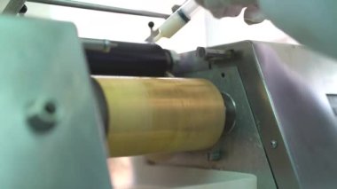 Birisi boya fabrikasındaki bir makineye beyaz sıvı enjekte ediyor.