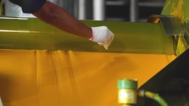 Birisi fabrikada yeni üretilen sarı renkten örnek alıyor.