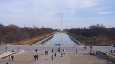 People Walking Down Stairs Near Water Source And Monument - Static