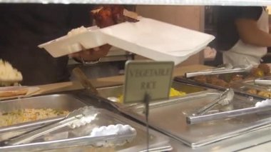 People Serving Food Near Vegetable Rice Sign - Slide - Left To Right