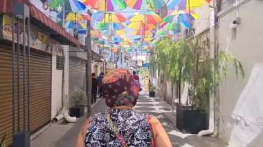Renkli şemsiyelerle sokakta yürüyen bir adam.