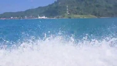 Açık bir günde dalgalı dalgalarla deniz suyunda hareket eden bir tekne.