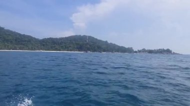 Yeşilliğin yakınındaki ferahlatıcı denizde ilerleyen bir gemi.