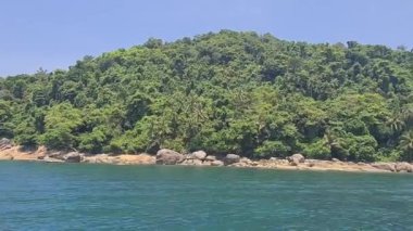 Huzurlu deniz manzarası ve sahildeki yeşil dağlar