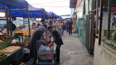 İnsanlar işlek bir cadde pazarındaki küçük dükkanlardan meyve alıyorlar