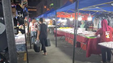 İnsanlar doğu pazarında tezgahların yanında yürüyorlar.