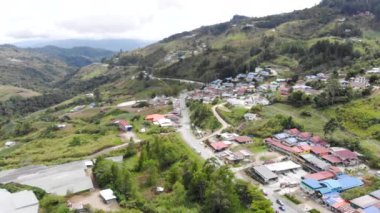 Yoğun yol manzarası, yakındaki evler yeşillik ve dağlar.