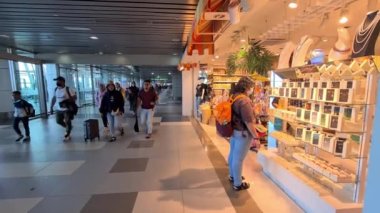 Sarı çantalı bir kadın havaalanından gümrüksüz mağazaya giriyor.