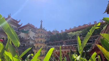 Güzel Kek Lok Tapınağı binası çimlerin arkasından görünüyor.