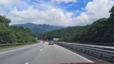 Bir otomobil penceresinden yeşilliklerle çevrili bir yol görüntüsü