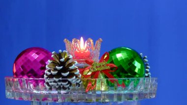 Cam bir zemin üzerinde mavi bir zemin, yanan bir mum etrafında Noel süslemeleri